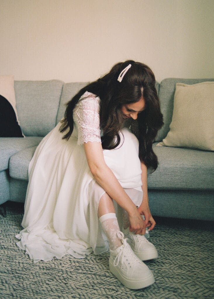 Bride putting on white sneakers on wedding day Helsinki, relaxed bridal style, Miss Moody Photography — Morsian laittaa valkoiset tennarit jalkaansa hääpäivänä Helsingissä, rento häätyyli, Miss Moody Photography