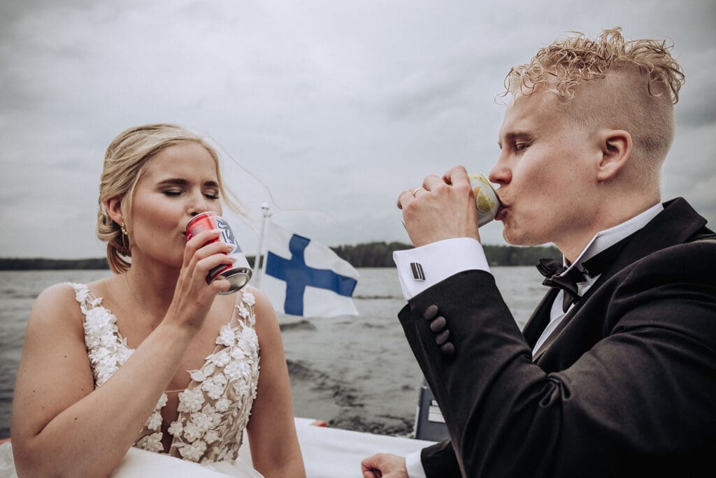 Bride and groom drinking champagne on a boat on the lake at Aurantola wedding in Jaala Kymenlaakso Finland, documentary wedding photography by Miss Moody Photography Finnish Australian wedding photographer | Morsian ja sulhanen samppanjaa veneessä Karijärvellä Aurantolan häissä Jaalassa Kymenlaaksossa, dokumentaarinen hääkuvaus Miss Moody Photography
