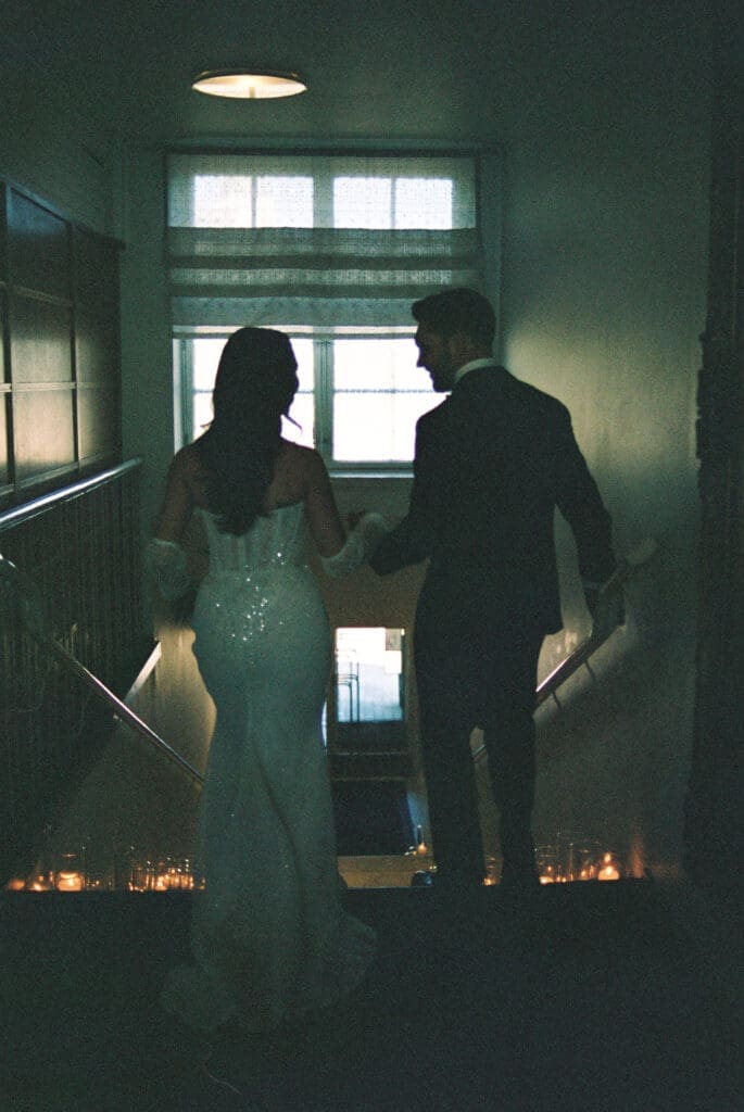 Bride and groom silhouette on candlelit staircase inside Kulosaari Casino Helsinki, moody film photography, Miss Moody Photography — Morsiamen ja sulhasen siluetti kynttilänvalaistuilla portailla Kulosaaren Casinon sisällä Helsingissä, tunnelmallinen filmivalokuvaus, Miss Moody Photography