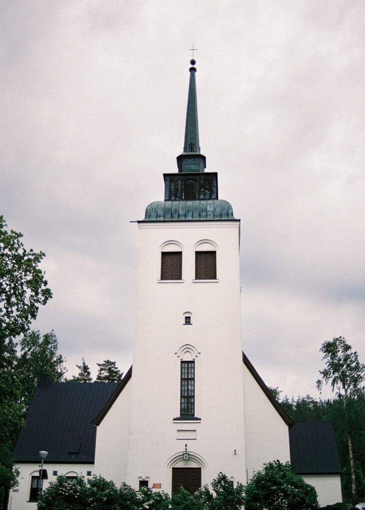 Valkeala kirkko white church exterior on a cloudy summer day, Finnish wedding photography by Miss Moody Photography | Valkealan kirkko valkoisena kesäpäivänä, hääkuvaus Miss Moody Photography Kymenlaakso