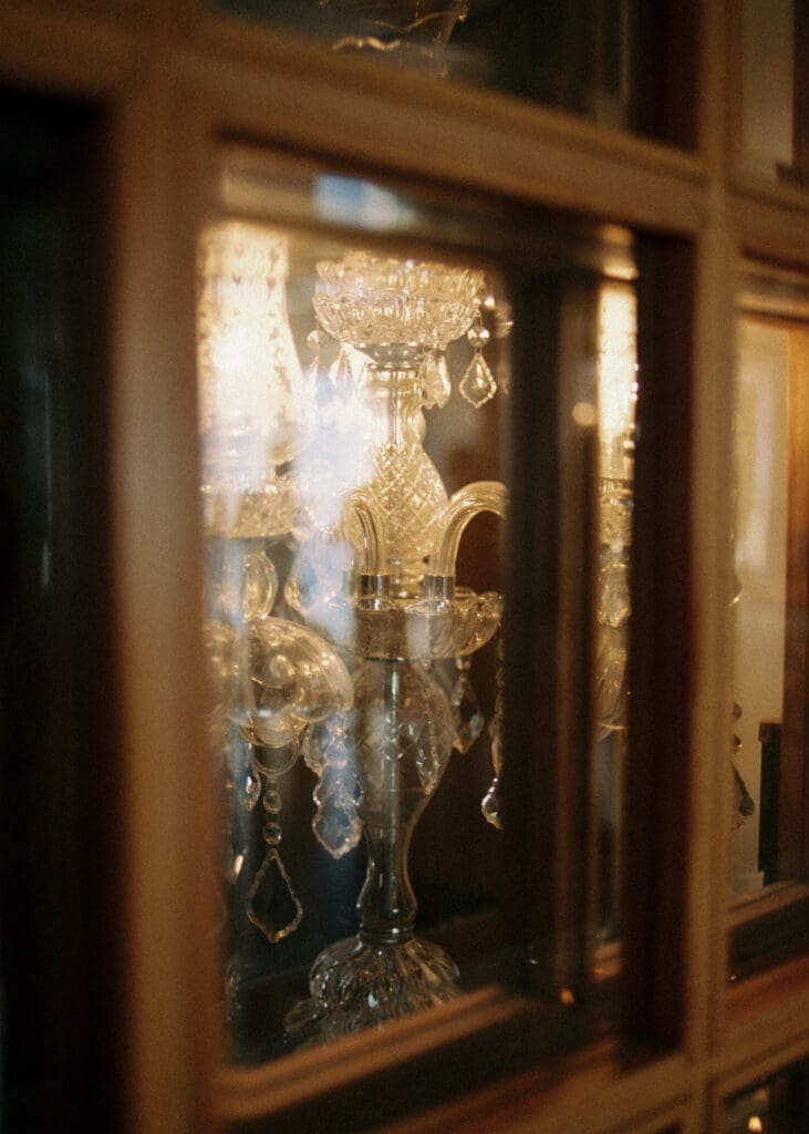 Crystal candelabra detail shot through glass cabinet at Kulosaari Casino Helsinki wedding venue, film photography, Miss Moody Photography — Kristallinen kynttelikköyksityiskohta lasikaapista Kulosaaren Casinon häävenueella Helsingissä, filmivalokuvaus, Miss Moody Photography
