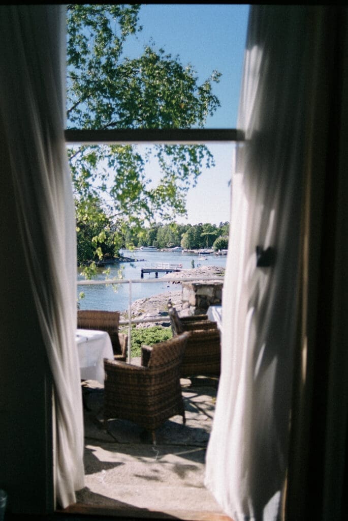 Kulosaari Casino Helsinki wedding venue view through open doorway to archipelago waterfront, film photography atmosphere, Miss Moody Photography — Kulosaaren Casinon häävenue Helsingissä avoimesta ovesta saaristoon, filmivalokuvaustunnelma, Miss Moody Photography