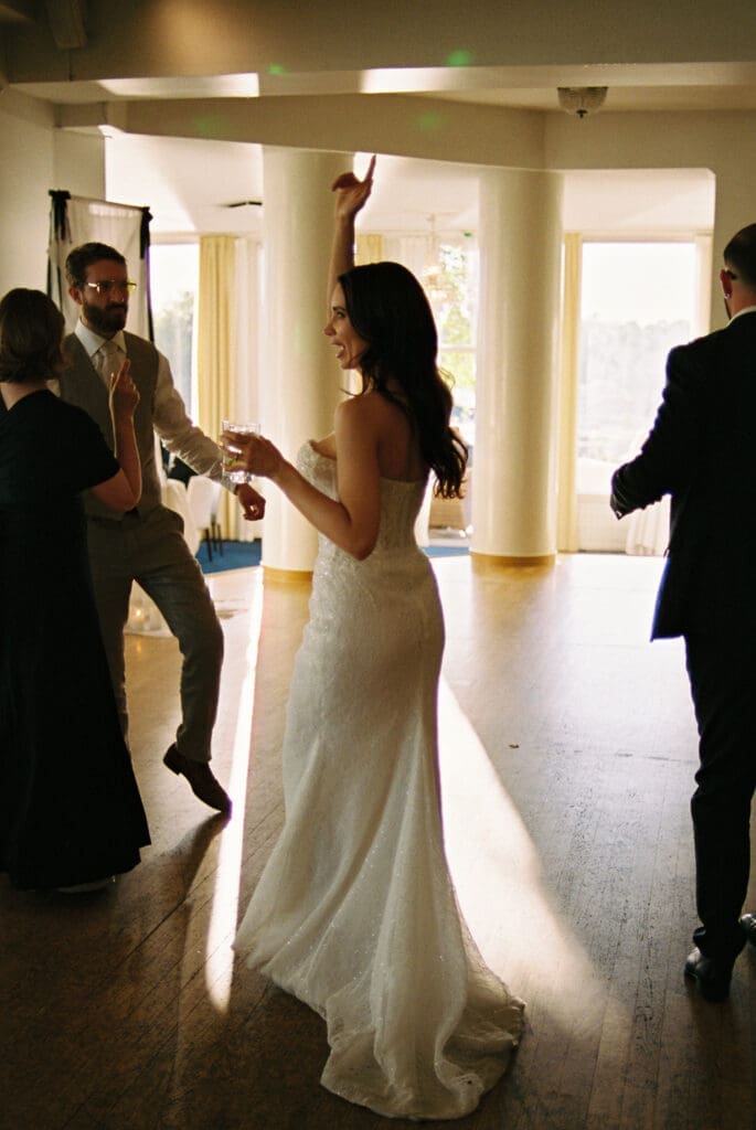 Bride dancing with hand raised at Kulosaari Casino Helsinki wedding reception, saxophone player in background, film photography, Miss Moody Photography — Morsian tanssii käsi koholla Kulosaaren Casinon häävastaanottolla Helsingissä, saksofonisti taustalla, filmivalokuvaus, Miss Moody Photography