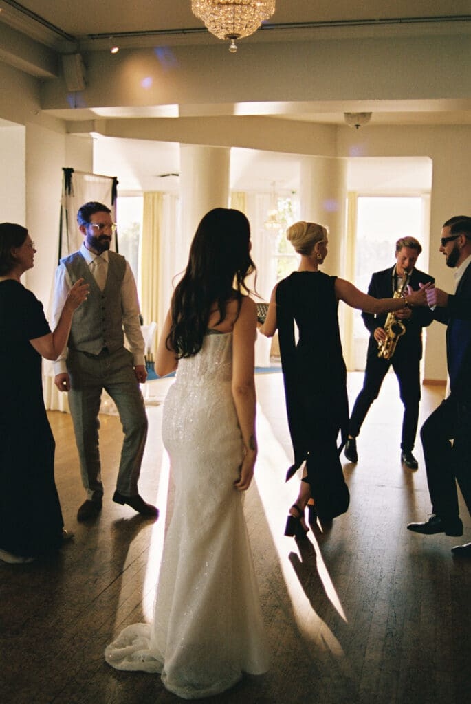 Bride dancing with guests and live saxophone player at Kulosaari Casino Helsinki wedding reception, film photography, Miss Moody Photography — Morsian tanssii vieraiden ja live-saksofonistin kanssa Kulosaaren Casinon häävastaanottolla Helsingissä, filmivalokuvaus, Miss Moody Photography