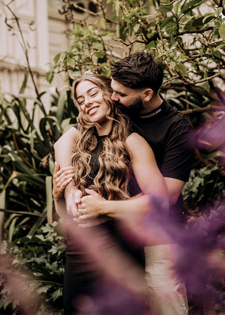 Couple embracing laughing under stone arch at Royal Exhibition Building Carlton Gardens Melbourne, engagement photography by Miss Moody Photography Melbourne wedding photographer