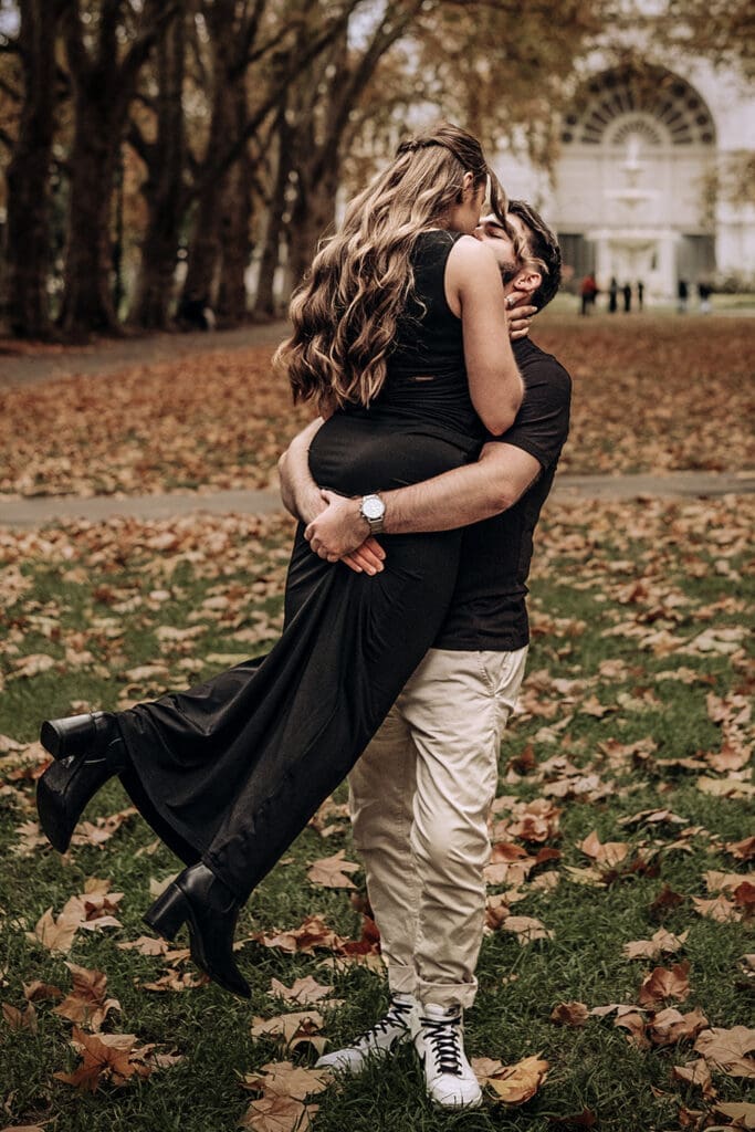 Couple spinning together in autumn leaves outside Royal Exhibition Building Carlton Gardens Melbourne, moody engagement photography Miss Moody Photography