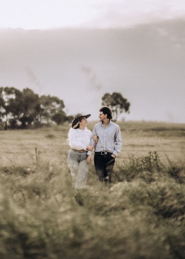 Engagement photo of a couple walking arm in arm through a paddock in Donald, Victoria