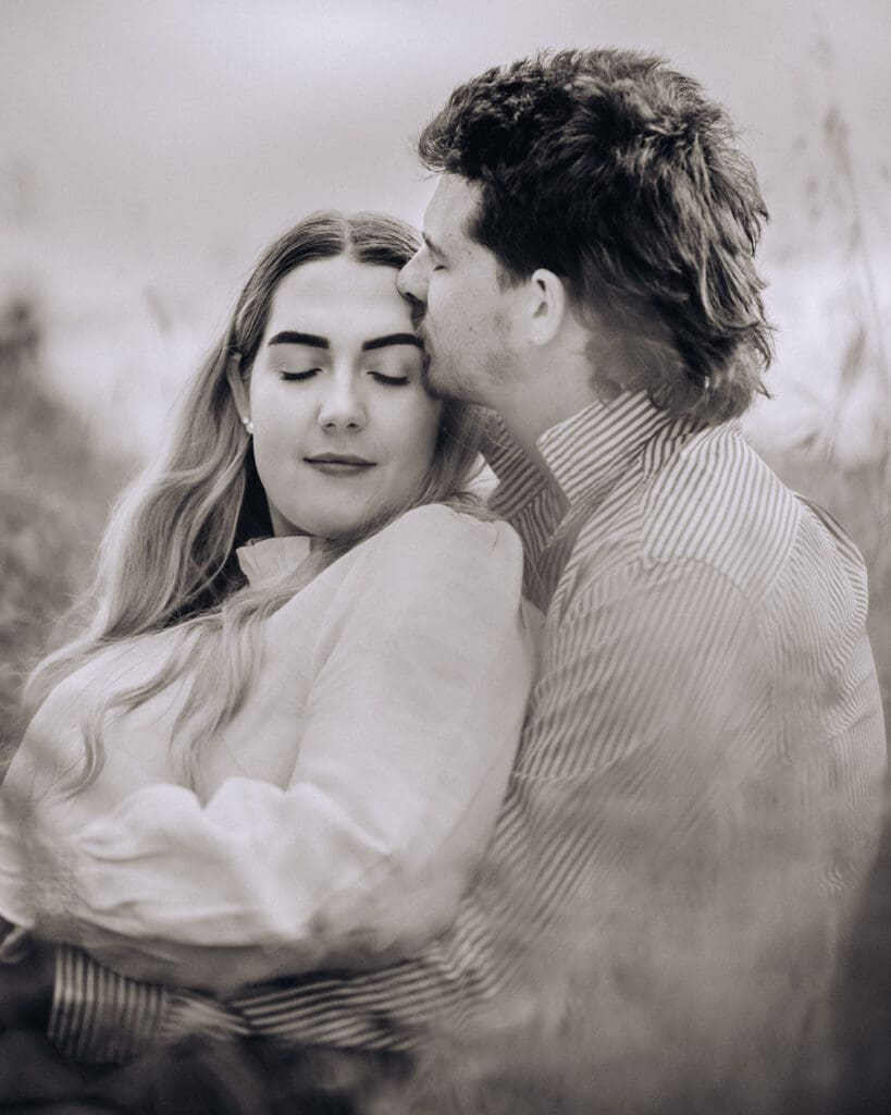 Close portrait of a couple in the grass, her eyes closed as he leans in beside her