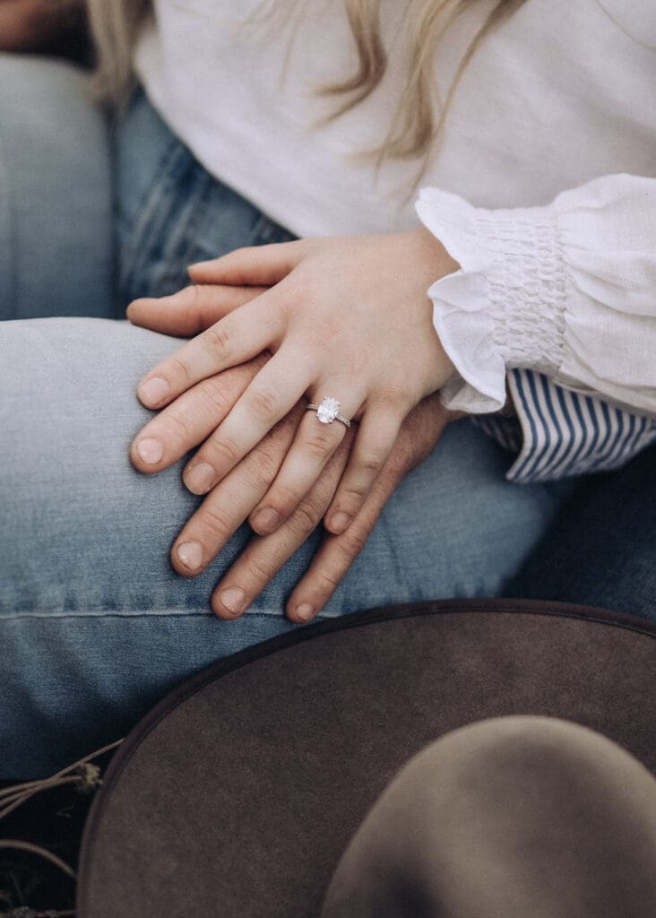 Close-up of an engaged couple holding hands, her engagement ring visible